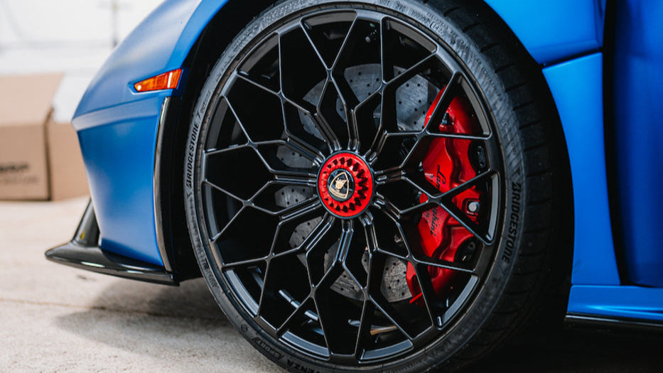 Lamborghini with black and red wheel design in a garage setting